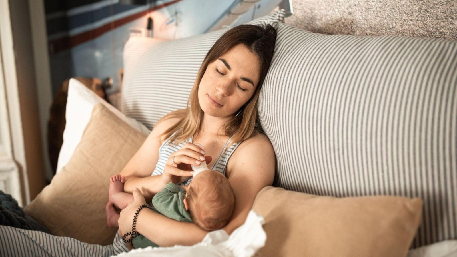 New mom nursing a newborn and enjoying a gift basket filled with food and practical gifts